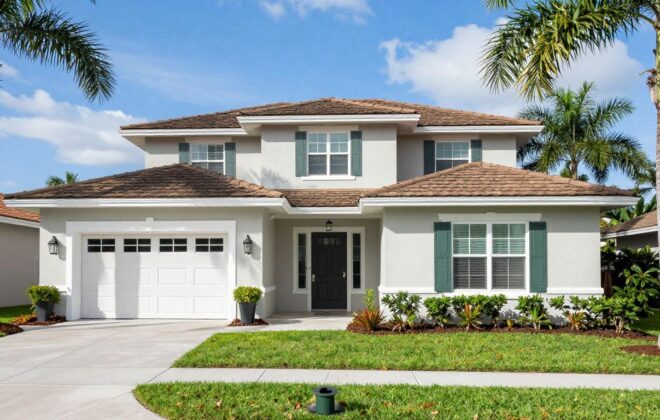 A beautiful Orlando home with a fresh coat of light-colored exterior paint under the sunny Florida sky, surrounded by palm trees.